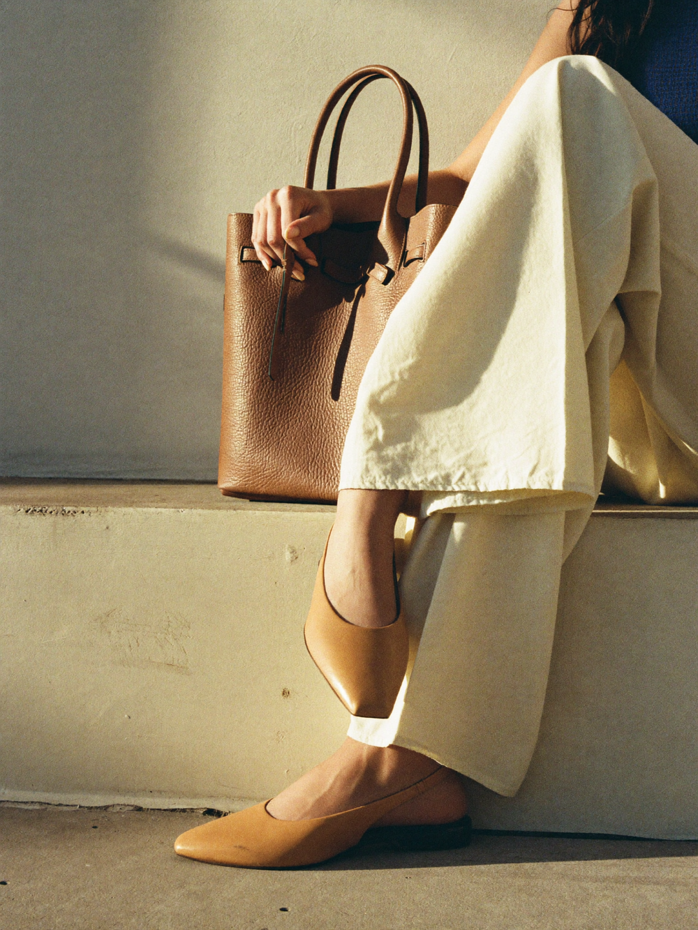 Camel leather tote bag and tan leather flats photographed in warm afternoon light